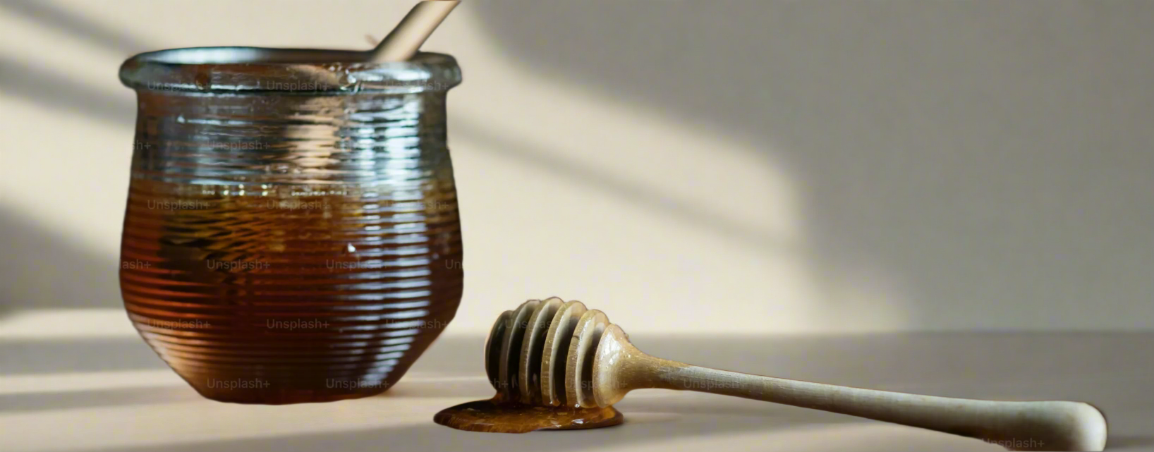 A honey pot and a dipper dipped with honey 